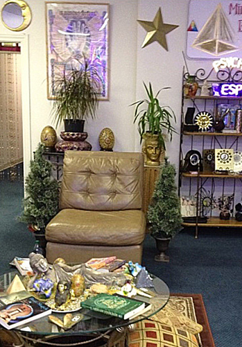 A chair surrounded by psychic decorations: palmistry artwork, moon and stars, a neon sign that reads ESP Psychic.